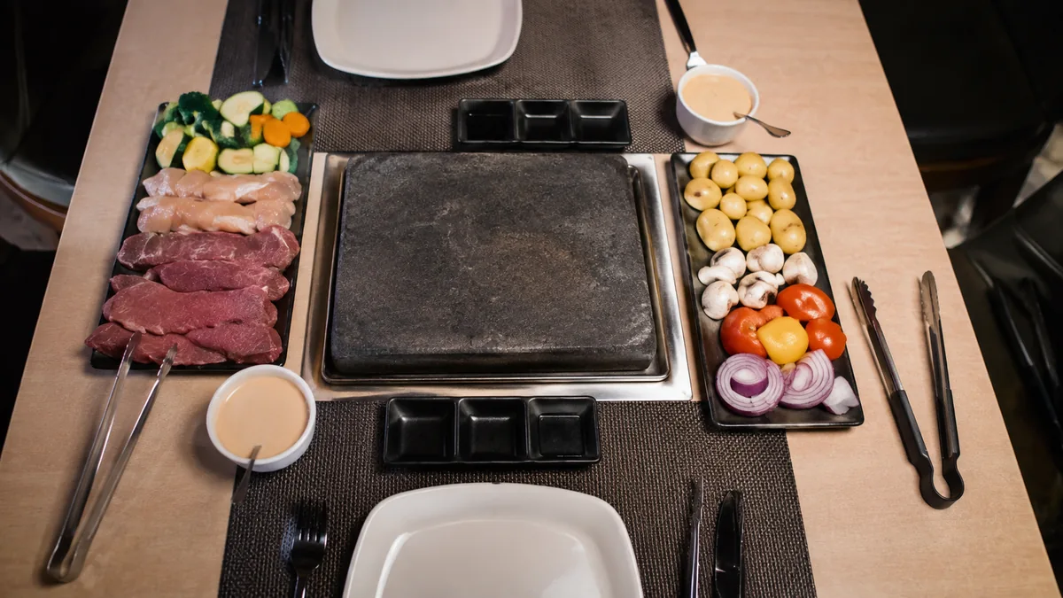 Table de pierrade avec viandes légumes sauces et pommes de terre